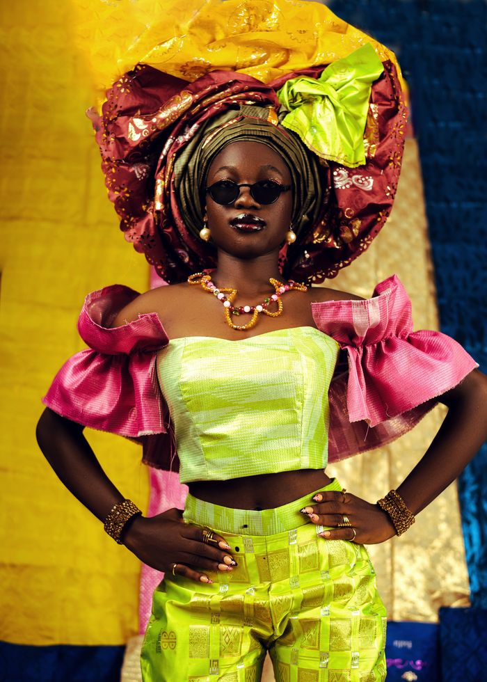 Colorful portrait of a woman in traditional African attire with Gele headwrap.